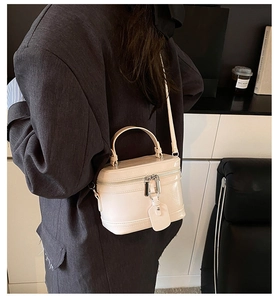 Close-up of a cream white PU leather box-style handbag with double zippers and strap