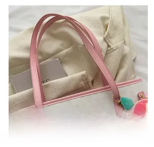 Close-up of white quilted tote bag featuring pink handles and a plush fruit charm