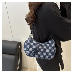 Dettaglio borsa a mezzaluna in denim a scacchi blu con bordi sfrangiati e mini ciondolo