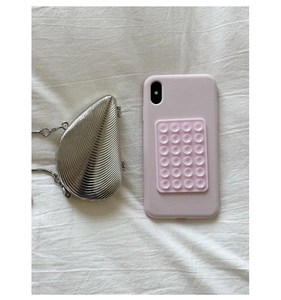 Silver shell-shaped evening clutch with radial texture and metal chain beside a smartphone