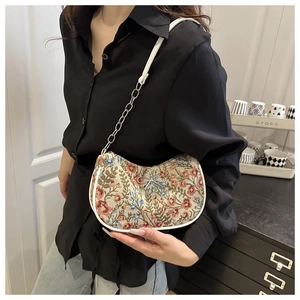 Détail du sac croissant à fleurs avec nœud argenté et bandoulière en chaîne métal