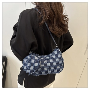 Dettaglio della borsa a mezzaluna in denim a scacchi blu con bordi sfrangiati