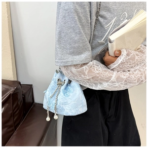 Detail of light blue butterfly embroidery on bucket bag with pearl and chain drawstring