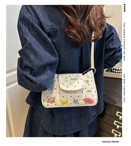 Detailed view of white polka dot crossbody bag with colorful cute cartoon patches on model