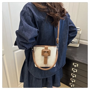Détail du sac seau en toile avec garniture en cuir marron et boucle en métal dorée