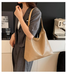 Detailed view of brown woven tote bag showing fine leather texture and wide shoulder strap