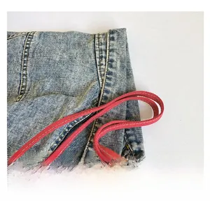 Makroaufnahme der blauen Denim-Tragetasche mit roten Webgriffen und feinen Nähten