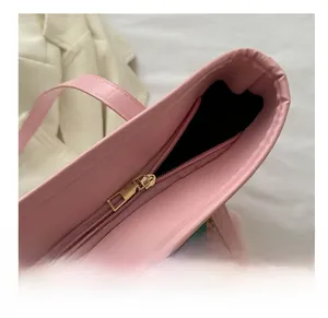 Close-up of a smooth gold metal zipper on a pink leather tote bag with black lining