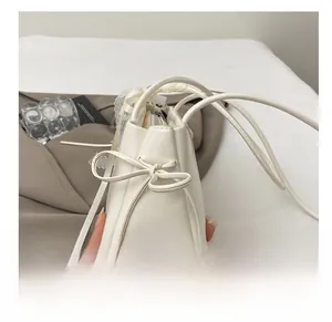 Détail d'un sac sous le bras en similicuir blanc avec nœud décoratif et poignée à cordon