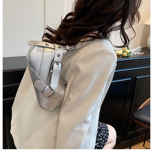 Detailed side view of a metallic silver saddle bag on a shoulder with rivet accents