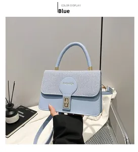 Detail of light blue crossbody bag with contrast texture and gold metal lock