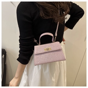 Pink sequin crossbody bag with gold lock shown by model in soft indoor lighting