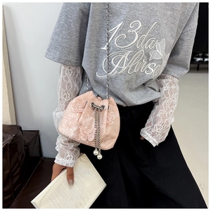 Détail d'un sac seau en dentelle rose avec broderies papillon et bandoulière chaîne