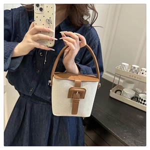 Détail du sac seau en toile avec poignée en cuir marron foncé et fermoir boucle