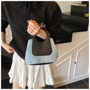 Detail of a chic color-block woven bucket bag with blue texture and black leather handle