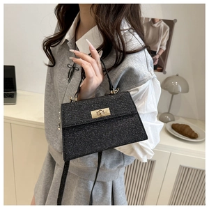 Close-up of black sequin handbag with gold twist lock and adjustable shoulder strap