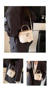 Detail view of cream mini box bag with top handle and metallic zip hardware details