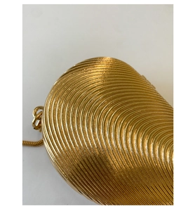 Detailed macro view of gold shell evening bag featuring radial stripes and metallic texture