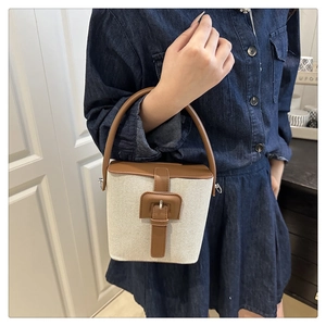 Détail du sac seau en toile crème minimaliste avec lanière en cuir marron et boucle