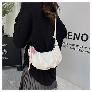 Detail of white pleated crescent bag with pink heart pendant and knotted strap detail