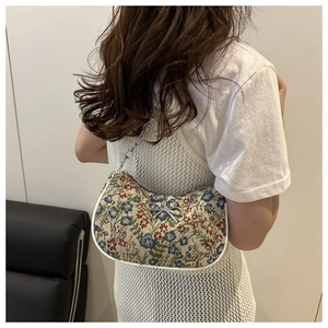 Détail du sac bandoulière jacquard floral avec nœud argenté et chaîne en métal