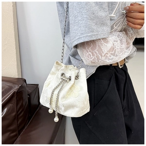 Close-up of floral lace bucket bag with pearl drawstrings and sleek metal chain strap