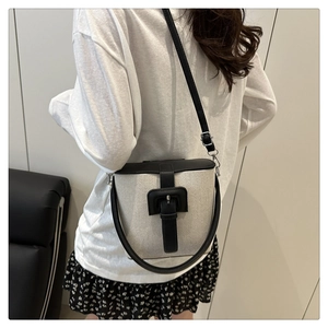 Gros plan du sac seau en toile beige avec finitions et fermoir en cuir noir élégant