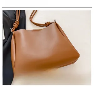 Détail de la bandoulière nouée et de la texture du cuir marron mat du sac fourre-tout