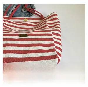 Detaillierte Makroansicht der rot-weiß gestreiften Canvas-Tasche mit goldenem Druckknopf