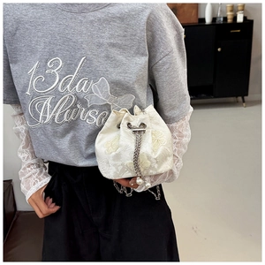 Détail de la broderie florale sur un sac seau crème avec cordon de serrage perle