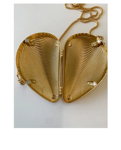Detail view of heart-shaped gold clutch with magnetic closure and wavy textured interior