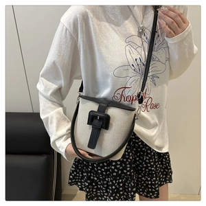Détail du sac seau en toile montrant les coutures en cuir et le fermoir à boucle