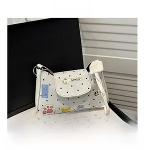 Close-up of a white polka dot handbag with colorful cat paw embroidery in a black gift box