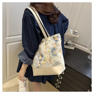 Dettaglio della borsa tote grande a fiori con frange indossata a spalla su una modella