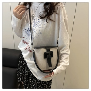 Détail du sac seau en toile avec finitions en cuir noir et boucle métallique