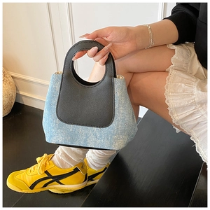 Detailed close-up of blue denim mini bucket bag with rhinestones and matte leather handle