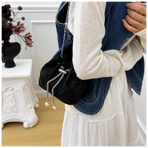 Détail du sac seau noir brodé avec chaîne argentée et ornements de perles blanches
