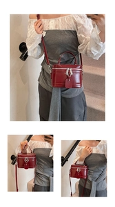 Macro detail of wine red square handbag with metallic zippers and textured leather