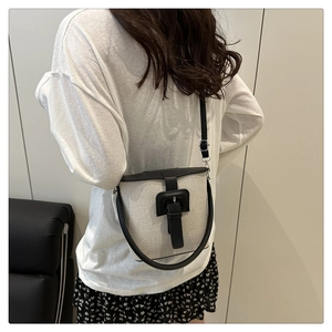 Sac seau chic en toile noir et blanc avec détails en cuir porté par un modèle