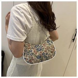 Détail de la broderie florale vintage sur le sac avec une boucle noeud argentée