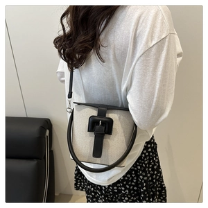 Détail du sac seau en toile minimaliste avec garniture en cuir noir et bandoulière