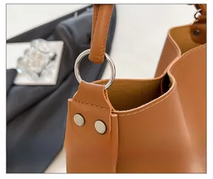 Détail macro de la boucle argentée et du rivet double sur sac seau en cuir marron