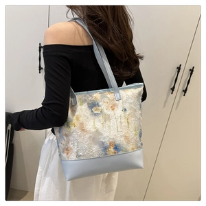 Detail of light blue tote bag featuring floral lace embroidery and faux leather textures