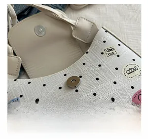 Detailed close-up of the secure silver magnetic metal buckle on a polka dot shoulder bag