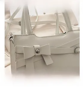 Gros plan d'un sac à main blanc en cuir avec un nœud élégant et un rivet métallique argenté