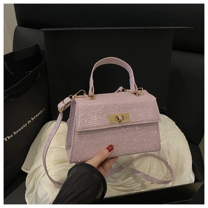 Close-up of glittery pink handbag with gold square lock on elegant silk lining