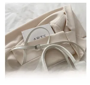 Gros plan d'un sac à main minimaliste en cuir blanc avec bandoulière réglable et détails argent