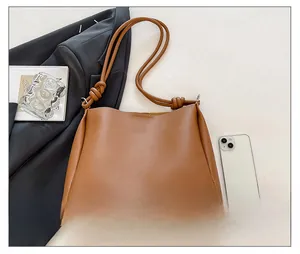 Détail du sac seau en cuir marron avec un design unique de bandoulière à nœud