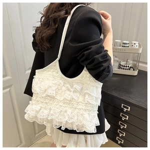 Detail of white lace tote bag with tiered ruffles and intricate embroidery details