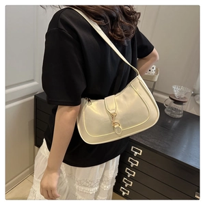 Detail of cream hobo shoulder bag with a polished gold buckle on smooth faux leather